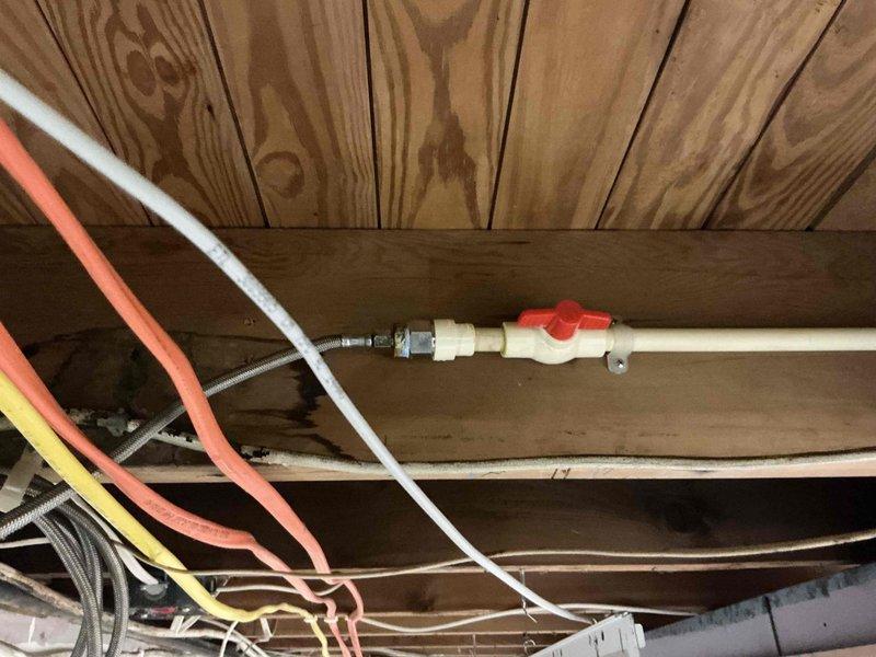 Responded to plumbing leak reported at shutoff valve location that began 3-4 days prior to service call. Upon arrival, conducted thorough inspection of the affected area and identified the source of the leak at the shutoff valve assembly connected to white PEX tubing in the crawlspace utility area. Documented existing conditions with photographs showing the valve configuration, surrounding utility lines including orange and white PEX tubing, yellow electrical conduit, and braided flexible supply lines. Assessed the water heater installation and surrounding plumbing infrastructure for any related issues or water damage. Noted evidence of moisture at the base of the water heater and floor discoloration consistent with the reported leak timeline. Performed necessary repairs to the leaking shutoff valve to restore proper function and eliminate water seepage. Verified all connections were secure and tested the system to confirm leak resolution before completing the service.
