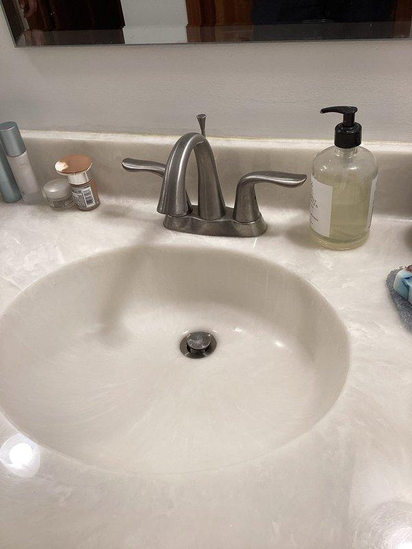 Installed new two-handle brushed nickel bathroom faucet with arched spout on existing vanity with undermount oval basin. Connected supply lines to existing shut-off valves beneath sink and tested for proper water flow and drainage. All connections verified leak-free and system operating correctly.
