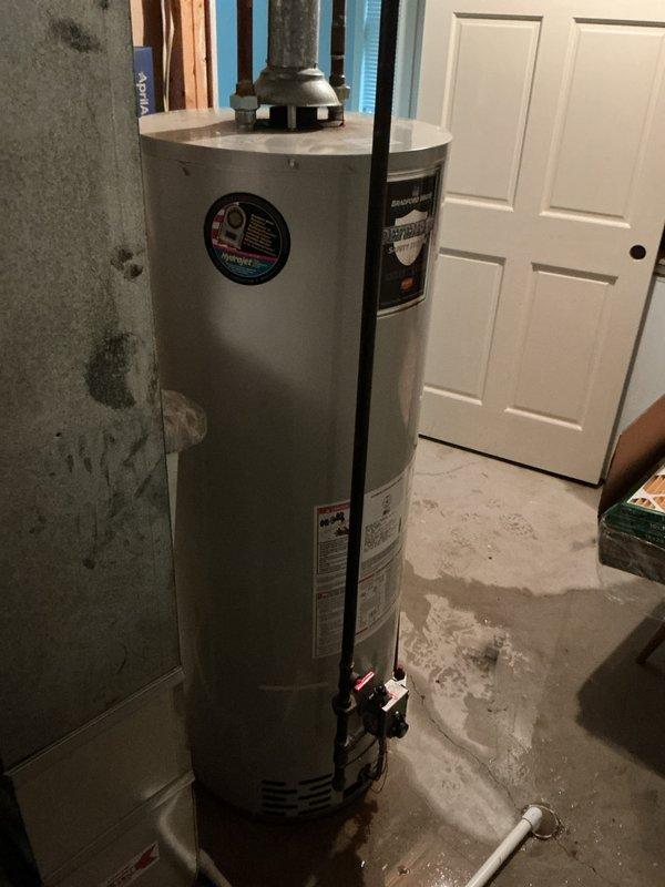 Responded to water leak emergency involving an 86-gallon EnergiAir water heater that had rusted through and was actively leaking. Upon arrival, found significant water damage on concrete floor and surrounding walls in basement utility area. Documented failed water heater unit with rust-through damage at base, along with existing plumbing connections and overhead ductwork configuration for replacement planning.