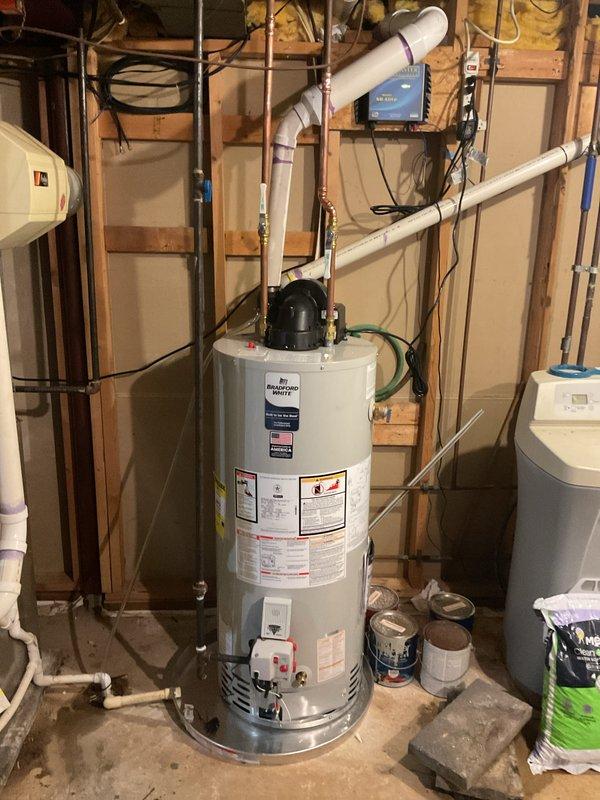 Completed installation of a 40-gallon Bradford White power vent LP gas water heater in basement utility area. Unit was properly connected to existing plumbing system with copper supply lines, PVC exhaust venting routed through ceiling, and all safety controls verified operational per manufacturer specifications.