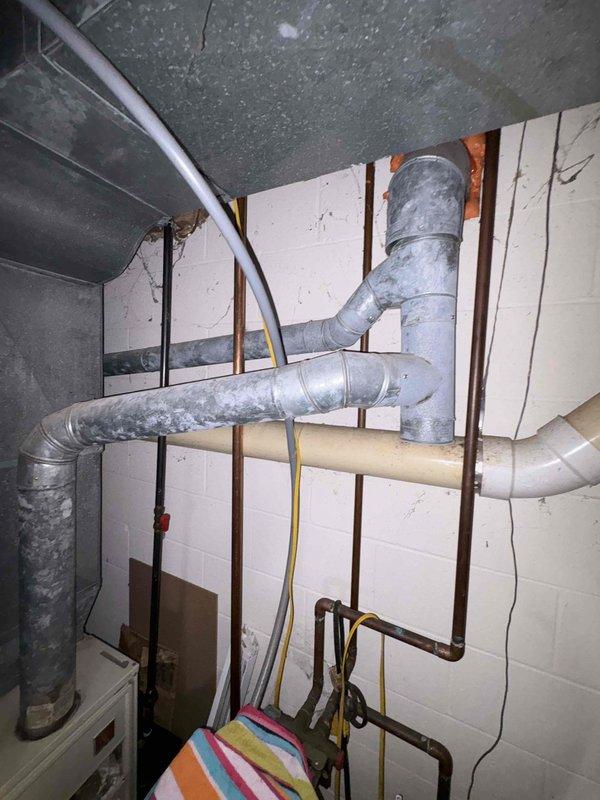 Responded to service call for water heater failure with active leak creating pooling water near unit in 40-year-old residential property. Upon arrival, conducted thorough assessment of standard tank water heater that had ceased heating operations approximately three days prior. Performed visual inspection of unit exterior, internal components, and surrounding plumbing connections to identify source of water leak and heating malfunction. Documented existing conditions through photographic evidence showing basement mechanical room layout, including exposed ductwork, plumbing lines, and utility infrastructure. Evaluated age and condition of water heater tank, checking for corrosion, sediment buildup, and structural integrity of vessel. Assessed all inlet and outlet connections, temperature and pressure relief valve, drain valve, and tank seams for potential leak points. Examined heating elements or burner assembly depending on unit type to determine cause of heating failure. Provided cust