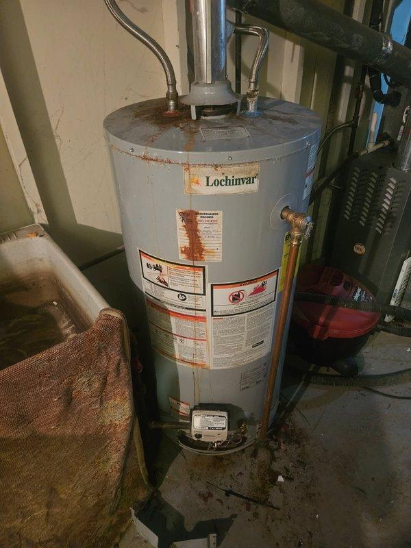 Conducted water heater replacement estimate for existing Lochinvar unit showing signs of age and corrosion, particularly around the top rim and metal components. Documented current installation configuration including copper supply lines, pressure relief valve piping, and surrounding HVAC infrastructure to provide accurate replacement specifications for customer-supplied equipment.