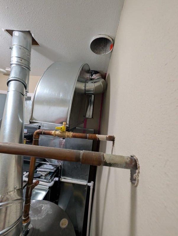 Performed no-charge assessment and reconfiguration of furnace and air conditioning system in residential mechanical room. Evaluated existing HVAC layout including black furnace unit with exposed internal components, cylindrical humidifier mounted on wall with flexible ductwork connection, and associated copper piping showing significant corrosion and oxidation. Reconfigured equipment positioning and connections to optimize system performance and accessibility for future maintenance.