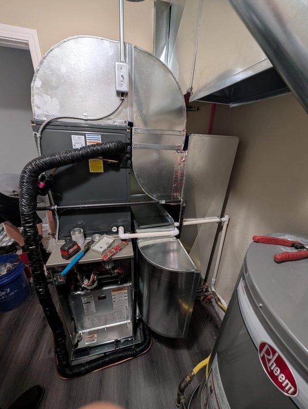 Performed no-charge assessment and reconfiguration of furnace and air conditioning system in residential mechanical room. Evaluated existing HVAC layout including black furnace unit with exposed internal components, cylindrical humidifier mounted on wall with flexible ductwork connection, and associated copper piping showing significant corrosion and oxidation. Reconfigured equipment positioning and connections to optimize system performance and accessibility for future maintenance.