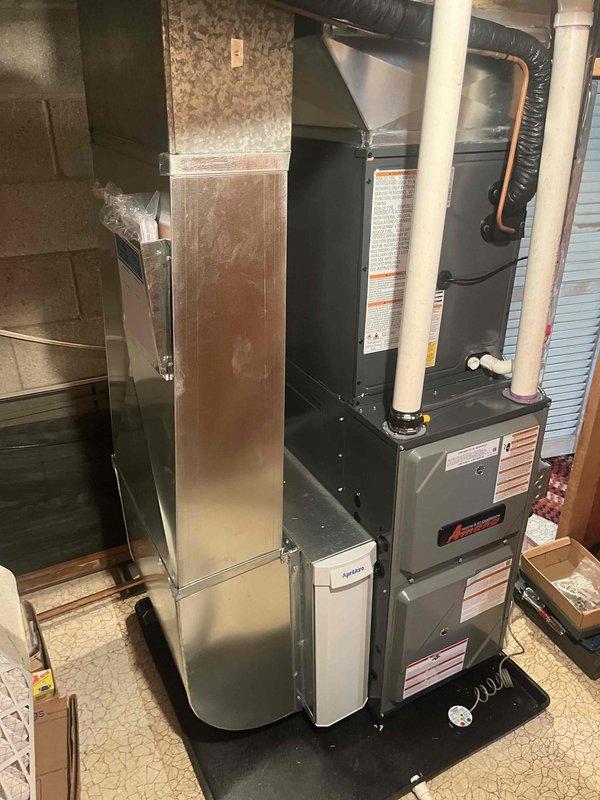 Completed full HVAC system installation consisting of an Amana furnace unit with accompanying air handler in utility room. Installed all required PVC intake and exhaust venting, copper refrigerant lines, and black flexible ductwork connections. Positioned equipment on protective drain pan with proper condensate drainage piping. All manufacturer specifications followed, safety labels verified, and system connections completed per code requirements.