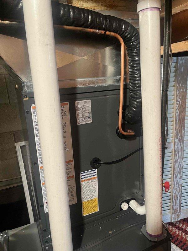 Completed full HVAC system installation consisting of an Amana furnace unit with accompanying air handler in utility room. Installed all required PVC intake and exhaust venting, copper refrigerant lines, and black flexible ductwork connections. Positioned equipment on protective drain pan with proper condensate drainage piping. All manufacturer specifications followed, safety labels verified, and system connections completed per code requirements.