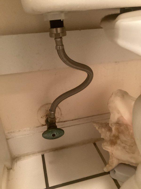 Responded to toilet issue in approximately 30-year-old residence. Inspected toilet tank interior and identified worn flush valve assembly with deteriorated red rubber flapper causing intermittent or incomplete flushing. Documented existing braided metal supply line connection, fill valve assembly, and mineral deposits consistent with age of fixture. Photographed tank components and water staining for service records.