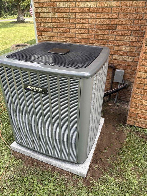 Completed full air conditioning system replacement at residential property. Removed existing outdoor condensing unit and installed new Enforcer brand AC unit on concrete pad against brick exterior wall, with proper electrical conduit and refrigerant line connections routed through wall penetration. Indoor furnace and coil system verified for compatibility with new outdoor unit. System fully charged with refrigerant, electrical connections tested and secured, all safety controls verified operational. Unit positioned on level concrete pad with adequate clearance for airflow and future service access. Final system startup completed with temperature differential and operational parameters confirmed within manufacturer specifications.