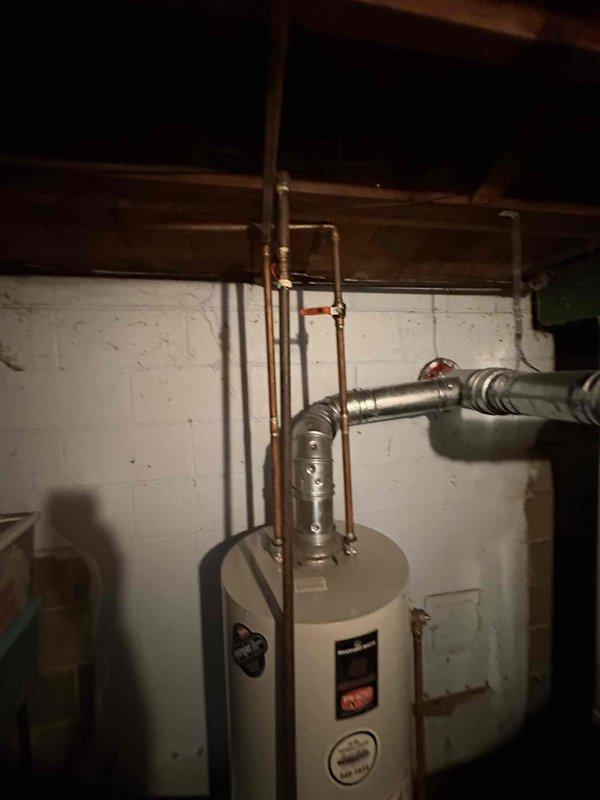 Responded to emergency call for flooded basement in 1960s-era home. Upon arrival, assessed standing water conditions in basement utility area and inspected water heater and associated copper plumbing lines for source of leak. Identified compromised plumbing connections near water heater with visible corrosion on brass fittings and joints. Shut off main water supply and drained affected lines. Replaced faulty brass connectors and tightened copper pipe joints at water heater connections. Tested system for leaks and restored water service. Additionally addressed secondary issue of multiple clogged drains throughout home. Cleared severely clogged sink drain using mechanical auger and cleared additional sink drains with cable snake equipment. Removed shower fixtures for access to drain assembly, cleared accumulated debris and mineral buildup causing slow drainage in shower basin. Reassembled fixtures and tested all drains for proper flow. Recommended customer monitor basement area for any r