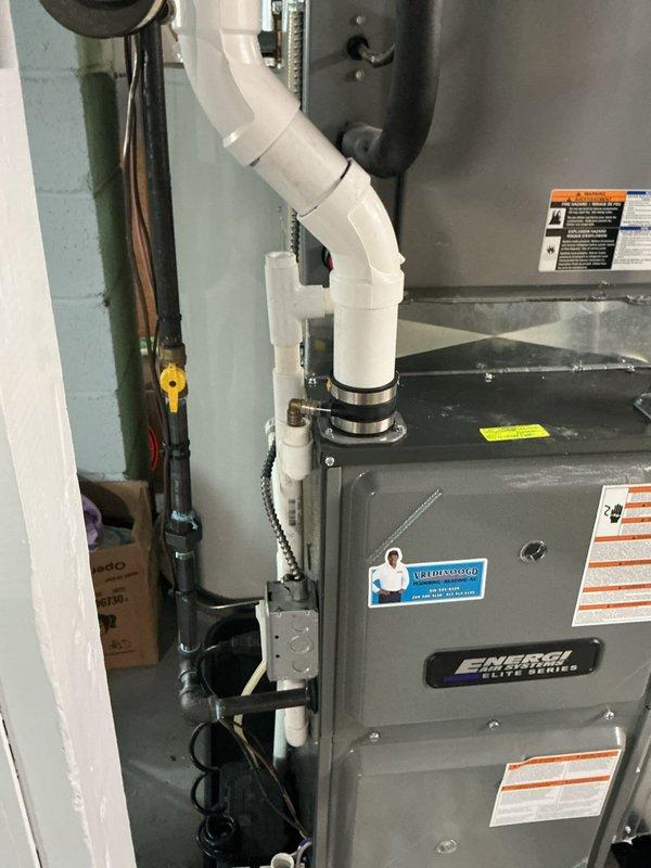 Responded to service call regarding cleanup required after previous appointment. Upon arrival, inspected HVAC system including Energi Elite Series furnace unit and associated condensate drain system with white PVC piping configuration. Documented current condition of mechanical room and equipment through photographic documentation. Cleaned utility area surrounding furnace and water heater installations, removing debris and organizing workspace. Verified all PVC condensate drain connections, coupling bands, and piping routes were properly secured. Inspected braided flex lines, yellow valve components, and vertical black piping runs for proper installation. Ensured all equipment labels and safety warnings remained visible and intact on furnace unit. Left mechanical room in clean, organized condition with all components properly positioned and accessible for future service needs.