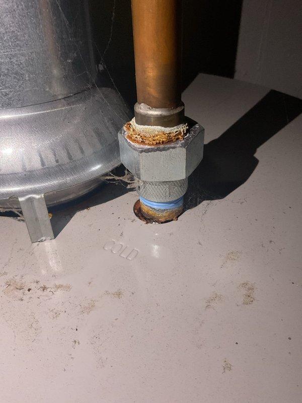 Responded to a water heater leak on a 6-year-old unit. Upon inspection, discovered significant rust and corrosion on the cold water inlet connection, including the dielectric union and threaded fittings. Documented the corroded components with photos showing deterioration around the pipe connections at the top of the tank, which was the source of the leak.