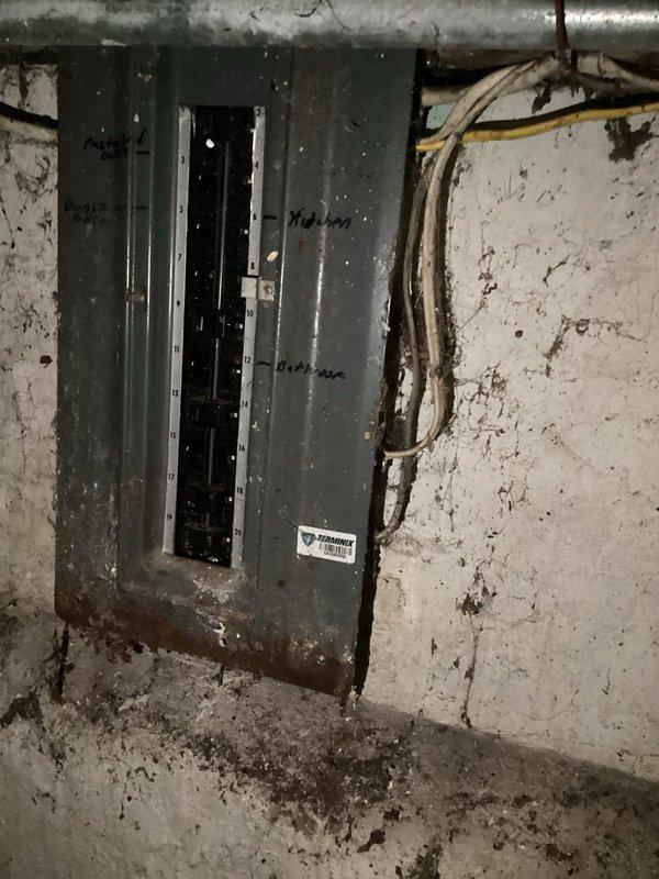 Completed comprehensive electrical assessment for full home rewiring estimate on 101-year-old residential property originally constructed in 1925. Evaluated existing electrical infrastructure including main service panel, meter base installation, interior distribution wiring, and junction boxes throughout dwelling. 

Documented current electrical panel condition showing aging circuit breaker configuration with deteriorated surrounding wall surfaces indicating potential moisture intrusion and structural concerns in utility area. Assessed exterior electrical service entrance components including meter enclosure, associated junction boxes, weatherhead connections, and service conduit runs. Identified need for complete electrical system replacement to bring property up to current code standards and ensure safe, reliable power distribution throughout residence. Provided detailed photographic documentation of existing conditions to support comprehensive rewiring proposal for entire home elec