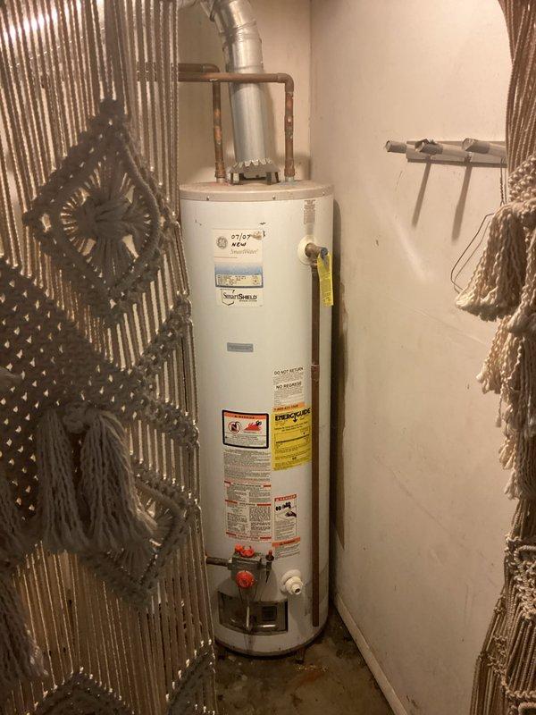 Responded to emergency call for water heater leaking from bottom of unit. Upon arrival, confirmed active leak from 19-year-old Goodman residential water heater. Inspected unit and determined tank failure due to age and internal corrosion. Documented existing installation with copper piping connections and venting configuration. Advised customer that water heater has exceeded typical service life and requires replacement due to compromised tank integrity.