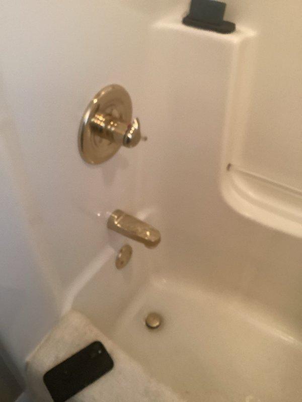Responded to bathtub leak in 23-year-old home affecting the tub and shower area. Inspected brass-finished single-handle shower control valve, combination tub spout with diverter, and associated plumbing connections in alcove-style bathtub installation. Accessed plumbing infrastructure beneath fixture area, examining copper supply lines, shutoff valves, and connections showing age-related corrosion and discoloration. Replaced faulty fixtures and components, addressed leak source, tested system operation to verify proper water flow and shutoff functionality, and documented repairs with photos for service records.