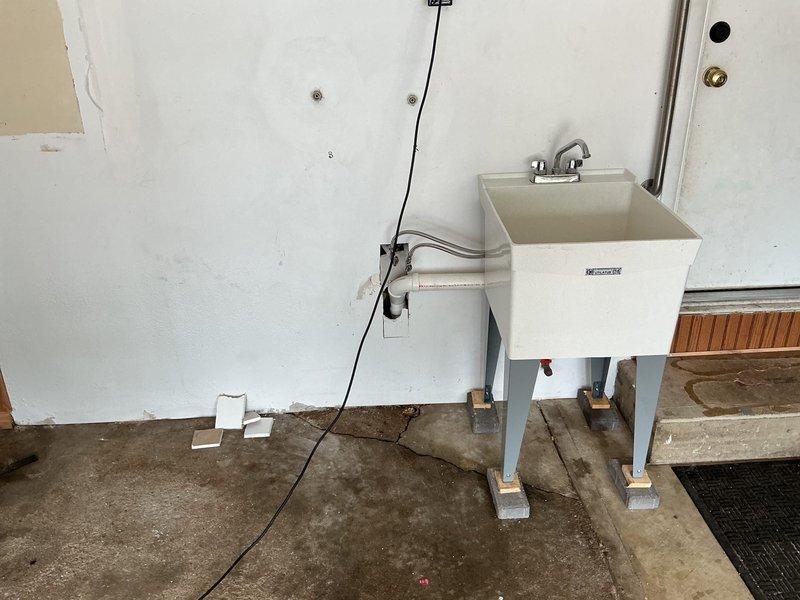Returned to complete previously quoted plumbing repair on utility sink drainage system. Elevated laundry tub basin using brick supports under metal leg footings to achieve proper trap height and eliminate standing water issues. Installed coupling to complete drain connection at corrected elevation, ensuring proper drainage flow and code-compliant trap configuration.