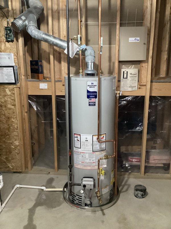 Completed installation of a Bradford White 50-gallon natural gas atmospheric vent water heater in residential basement utility area. Unit was positioned on concrete floor with proper clearances, connected copper water supply lines to hot and cold ports, and installed galvanized metal B-vent exhaust system with appropriate pitch and termination. All gas connections were made per manufacturer specifications at 4.0" W.C. manifold pressure, pressure tested for leaks, and verified proper combustion and venting operation upon startup.