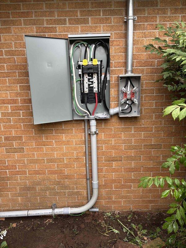 Completed 200-amp electrical service upgrade and subpanel installation on residential property. Coordinated utility disconnect and reconnect service to safely perform main service panel replacement. Installed new 200-amp main breaker panel with properly organized circuit breakers, bus bar assembly, and grounding system mounted on exterior brick wall. Routed service entrance conductors through metallic conduits from utility connection point to new meter base and main panel. Installed electrical disconnect box and completed all associated conduit work, including PVC ground-level runs. All wiring color-coded and secured per NEC standards with green grounding conductors, white neutrals, and black/red hot conductors properly terminated. Addressed client concerns regarding non-functioning outlets and clarified installation specifications for newly installed receptacles that appeared to protrude further than expected due to code-compliant box depth requirements. Obtained electrical permit and