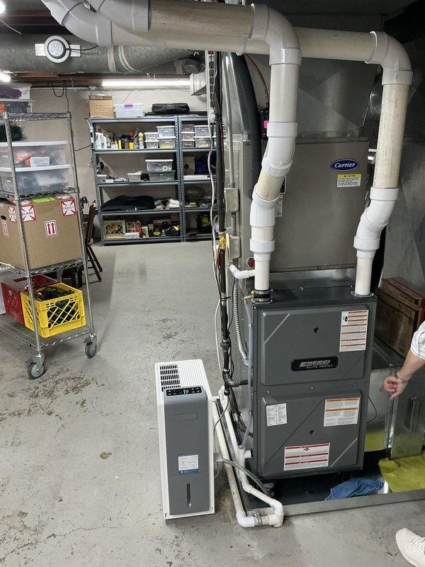 Responded to service call for air conditioning system with physical damage from fallen tree and cooling performance issues. Upon inspection, found outdoor condensing unit sustained minor dent to cabinet but remained operational. Diagnosed slow refrigerant leak in suction line causing low system charge and frozen evaporator coil. System comprised 2007 evaporator coil paired with 2012 heat pump unit. 

Performed temporary repair to restore immediate cooling functionality prior to customer travel. Provided estimate for complete 4-ton system replacement to be scheduled upon customer's return. Documented equipment condition with interior and exterior photographs showing basement HVAC installation and outdoor condensing unit placement. Customer elected to proceed with temporary repair and full system replacement at later date.