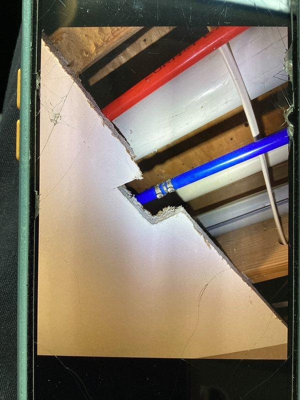 Responded to plumbing leak caused by restoration company damage to PEX water line in ceiling. Upon arrival, found active water dripping from damaged pipe where it had been accidentally nicked during restoration work. Assessed the situation and documented the damage with photographs showing red and blue PEX supply lines running through ceiling joists with visible moisture accumulation and water droplet formation at the point of damage. Coordinated repair with restoration company who accepted responsibility for the incident. Completed necessary repairs to restore water service and prevent further water damage to the structure.