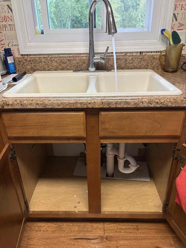 Replaced malfunctioning kitchen faucet with customer-supplied chrome pull-down unit on double-basin white sink. Removed existing faucet that was difficult to operate, installed new faucet assembly with proper mounting and connections, verified water flow and drainage system functionality, and confirmed no leaks at supply lines or drain connections.