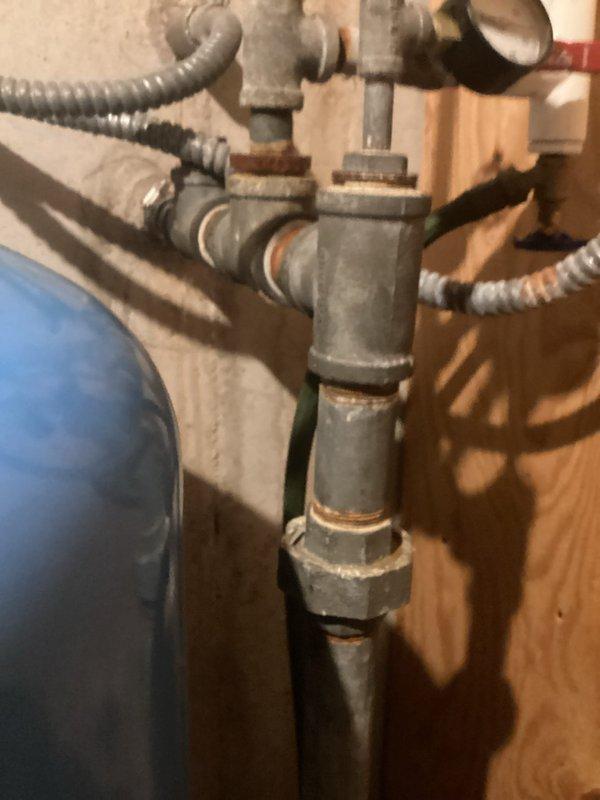 Conducted on-site assessment of existing well pressure tank system for replacement estimate. Inspected current blue pressure tank installation showing signs of age and corrosion on pipe fittings, threaded connections, and union joints. Evaluated plumbing configuration including gray metal pipes, flexible conduits, pressure gauge assembly, and electrical components. Documented existing system layout and condition through photographic documentation to provide accurate estimate for new bladder/pressure tank replacement.