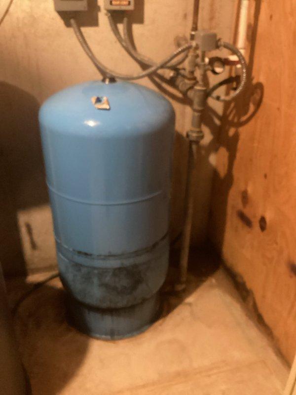 Conducted on-site assessment of existing well pressure tank system for replacement estimate. Inspected current blue pressure tank installation showing signs of age and corrosion on pipe fittings, threaded connections, and union joints. Evaluated plumbing configuration including gray metal pipes, flexible conduits, pressure gauge assembly, and electrical components. Documented existing system layout and condition through photographic documentation to provide accurate estimate for new bladder/pressure tank replacement.
