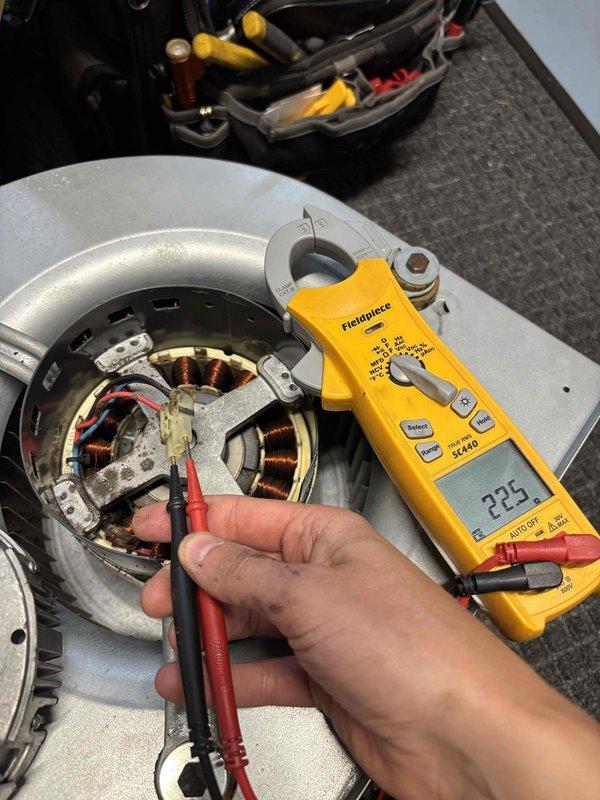 Responded to no cooling call for bedroom unit. Upon arrival, found blower motor inoperative while other units in home functioning normally. Disassembled blower assembly and performed electrical diagnostics using multimeter to test motor windings and connections. Tested amperage draw with clamp meter and inspected internal copper windings and capacitor connections. Motor exhibited failed windings consistent with age-related failure on 2017 equipment. Documented findings with photos showing disassembled motor assembly with exposed stator coils and electrical testing in progress. Provided customer with repair options for failed blower motor replacement.