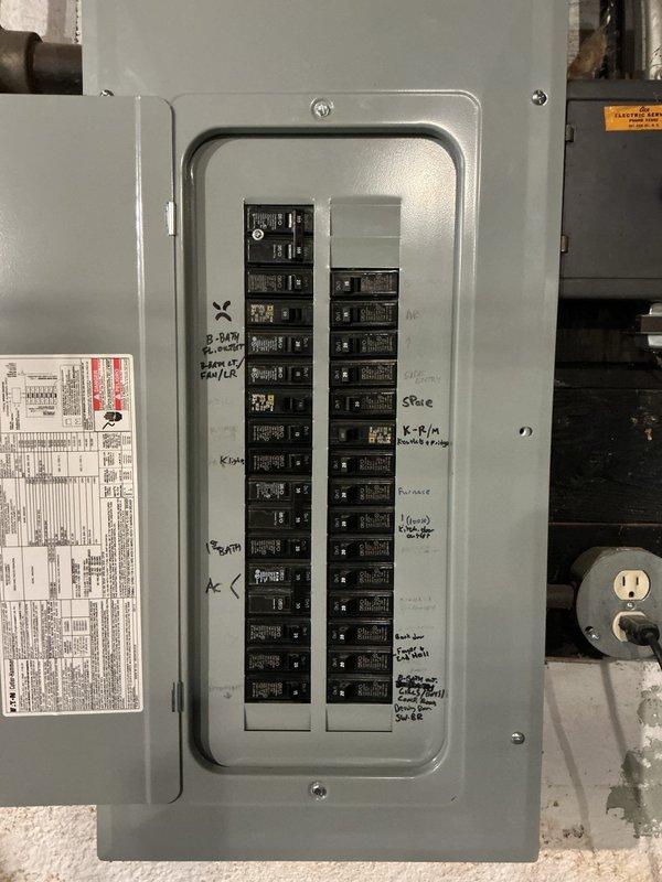 Conducted on-site assessment for Level 2 electric vehicle charger installation at a 99-year-old residential property. Documented existing electrical infrastructure, including the main service panel with dual columns of circuit breakers, incoming service conduits, and available capacity for additional load requirements. Photographed current electrical panel configuration to evaluate compatibility and determine necessary upgrades for EV charging system integration.
