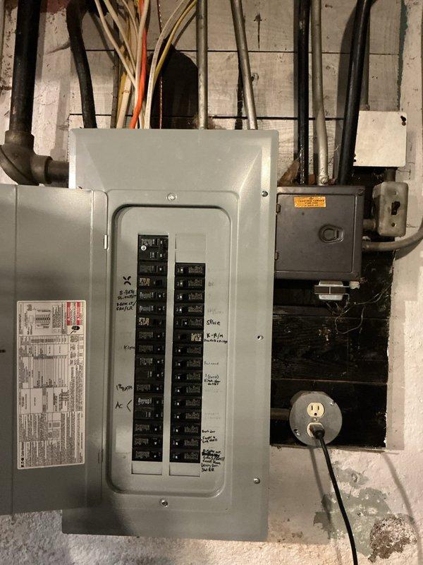 Conducted on-site assessment for Level 2 electric vehicle charger installation at a 99-year-old residential property. Documented existing electrical infrastructure, including the main service panel with dual columns of circuit breakers, incoming service conduits, and available capacity for additional load requirements. Photographed current electrical panel configuration to evaluate compatibility and determine necessary upgrades for EV charging system integration.