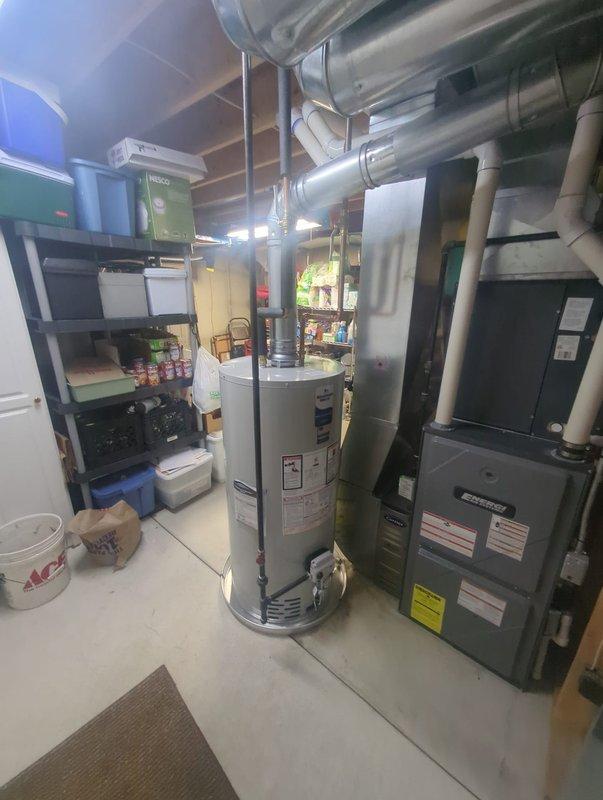 Completed water heater installation in basement mechanical room. Removed existing unit and installed new cylindrical water heater with proper copper piping connections, ensuring all plumbing configurations met code requirements. Connected supply and discharge lines, installed temperature and pressure relief valve, and verified all connections for leak-free operation. Unit positioned adjacent to existing furnace system with adequate clearance for service access and proper ventilation. System tested and confirmed operational with appropriate water temperature settings.