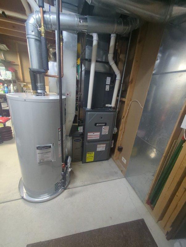 Completed water heater installation in basement mechanical room. Removed existing unit and installed new cylindrical water heater with proper copper piping connections, ensuring all plumbing configurations met code requirements. Connected supply and discharge lines, installed temperature and pressure relief valve, and verified all connections for leak-free operation. Unit positioned adjacent to existing furnace system with adequate clearance for service access and proper ventilation. System tested and confirmed operational with appropriate water temperature settings.