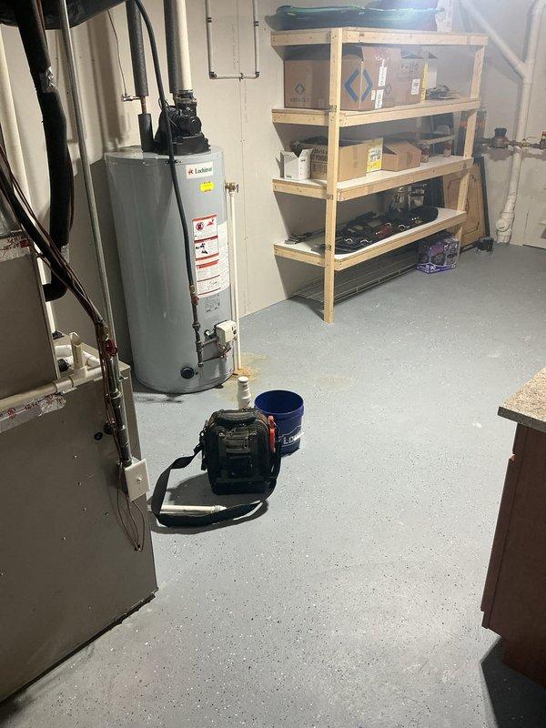 Responded to service call for 11-year-old Lochinvar water heater experiencing intermittent hot water supply. Upon inspection, observed water staining on floor near base of unit and evaluated circulation pump assembly and plumbing connections at top of heater. Documented equipment condition with photos showing all piping connections, insulated lines, and electrical components for further diagnostic assessment and customer records.