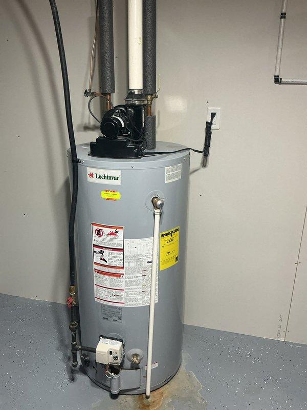 Responded to service call for 11-year-old Lochinvar water heater experiencing intermittent hot water supply. Upon inspection, observed water staining on floor near base of unit and evaluated circulation pump assembly and plumbing connections at top of heater. Documented equipment condition with photos showing all piping connections, insulated lines, and electrical components for further diagnostic assessment and customer records.