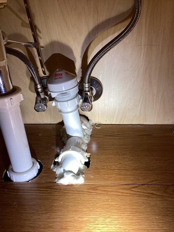 Responded to guest bathroom plumbing concern regarding white foam material protruding from drain pipe connections beneath sink. Upon inspection, found excessive expanding foam sealant had been previously applied around PVC drain assembly joints, creating irregular bulbous formations at pipe connections. Assessed toilet operation as requested and confirmed proper functionality with no issues identified.