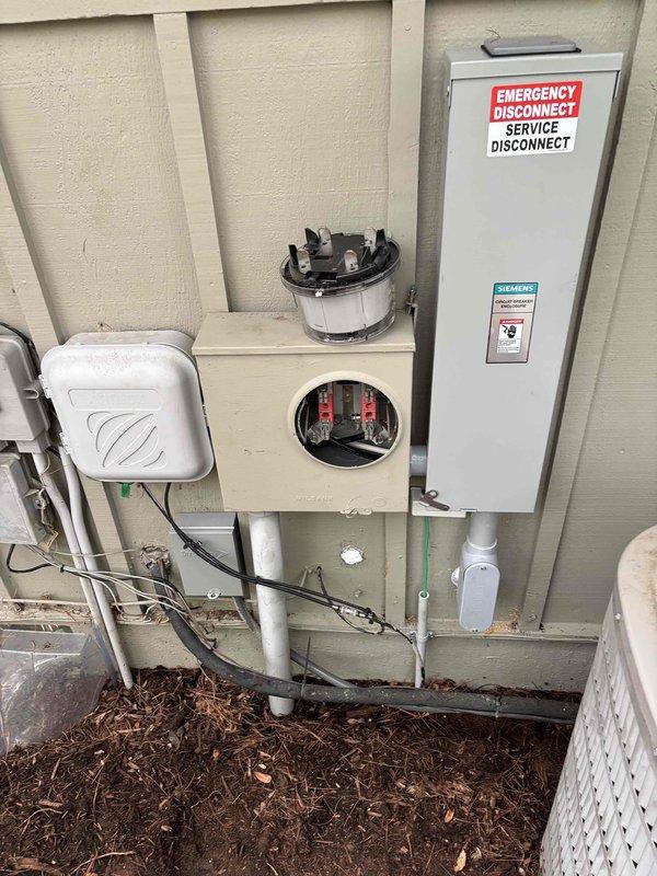 Completed 150-amp electrical service upgrade including installation of new main breaker panel, exterior emergency disconnect switch, and associated metering equipment. Coordinated utility disconnect and reconnect services, obtained electrical permit, and passed final inspection. Installed gray breaker panel on wooden backing in basement utility area with proper cable routing, mounted Siemens-branded exterior emergency disconnect on building exterior with weather-resistant enclosures, and integrated digital monitoring controller for system management.