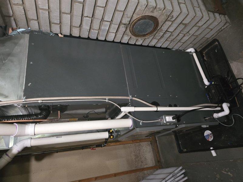 Completed full HVAC system installation including new air handler unit, electrical service panel upgrade, and humidifier integration in residential basement utility area. Coordinated utility company power disconnect and reconnect services to facilitate safe electrical panel replacement. Obtained electrical permit and scheduled inspection with local building authority. Installed vertical air handler with PVC condensate drain lines and armored electrical conduit. Integrated whole-home humidifier unit with copper piping connections to main ductwork system. Completed all electrical connections through new junction box and conduit runs. Verified proper drainage, airflow, and electrical connections throughout system. All work performed to code requirements and passed scheduled electrical inspection.