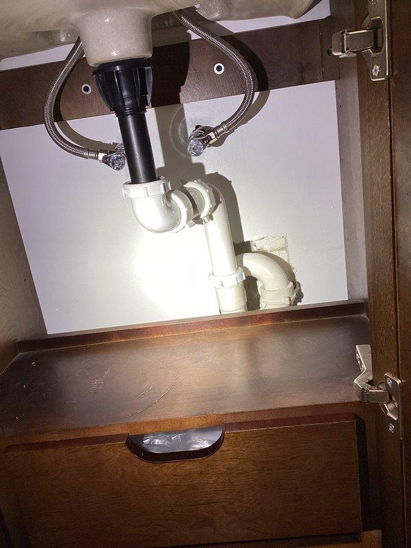 Responded to service call for under sink plumbing inspection and evaluation. Performed thorough assessment of kitchen sink drain system, including P-trap assembly, PVC waste line connections, and basket strainer configuration. Documented existing plumbing conditions with photographs showing vertical drain pipe with rubber coupling connection and complete under-cabinet plumbing layout including flexible braided supply lines. Provided estimate for sewer scoping services and dryer vent replacement as requested.