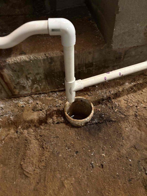Responded to investigate furnace condensate drain issue as recommended by HVAC technician. Upon inspection, found basement floor drain receiving discharge from furnace drain line was experiencing drainage problems. Examined white PVC drain piping configuration with P-trap assembly connected to floor drain opening. Observed standing water in drain and significant moisture damage on surrounding concrete block walls, indicating chronic drainage concerns. Photographed piping layout and floor drain condition showing water accumulation and debris. Drain system requires further evaluation to determine if blockage is in floor drain trap, main building drain line, or if drain capacity is insufficient for condensate volume. Furnace heating and cooling functions remain operational at time of inspection.