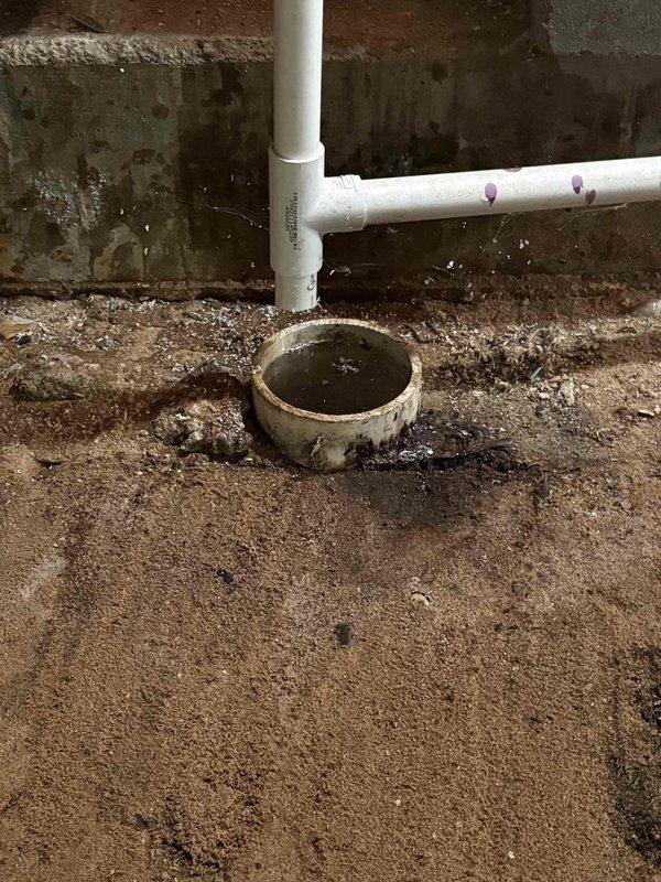Responded to investigate furnace condensate drain issue as recommended by HVAC technician. Upon inspection, found basement floor drain receiving discharge from furnace drain line was experiencing drainage problems. Examined white PVC drain piping configuration with P-trap assembly connected to floor drain opening. Observed standing water in drain and significant moisture damage on surrounding concrete block walls, indicating chronic drainage concerns. Photographed piping layout and floor drain condition showing water accumulation and debris. Drain system requires further evaluation to determine if blockage is in floor drain trap, main building drain line, or if drain capacity is insufficient for condensate volume. Furnace heating and cooling functions remain operational at time of inspection.