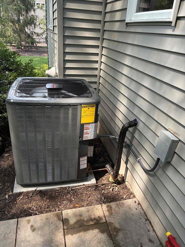 Completed full air conditioning system replacement at residential property. New outdoor condensing unit installed on existing concrete pad against exterior wall, with proper refrigerant line connections to indoor air handler. System charged with total of 108 oz of refrigerant (88 oz factory charge plus 20 oz field charge), electrical disconnect properly mounted, and all connections tested and verified operational.