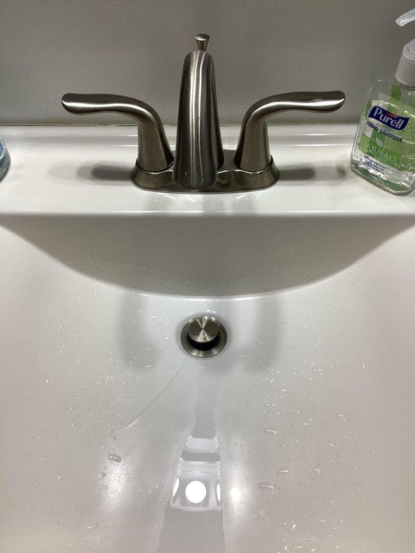 Completed faucet repair at residential bathroom sink. Installed new brushed nickel three-piece faucet assembly with dual handles and center spout. Inspected under-sink plumbing connections, verified proper function of PVC drain lines and supply line connections, and ensured all components were secure and leak-free.