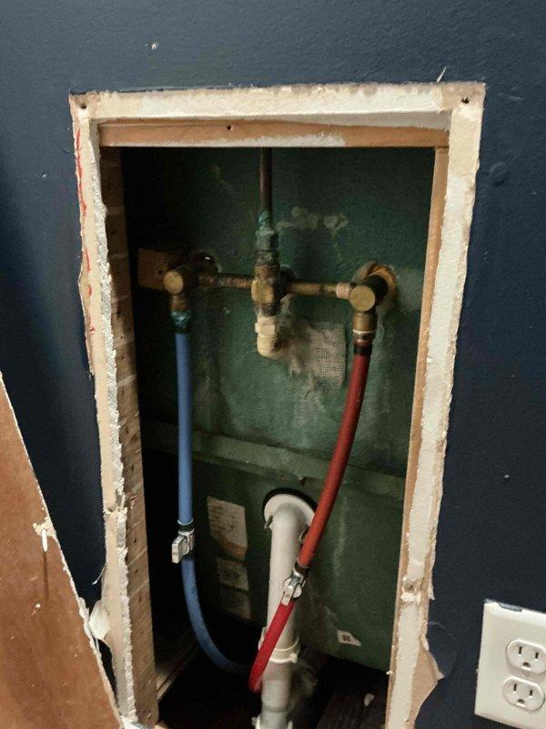 Responded to service call for stripped cold water handle screw causing faucet to stick in on/off positions. Created wall access opening to expose supply line connections and plumbing infrastructure behind affected fixture. Inspected brass fittings, flexible supply lines (hot and cold), and drainage connections within wall cavity. Documented existing plumbing configuration including PEX tubing, shutoff valves, and trap assembly for historic property. Access point prepared for faucet handle replacement or complete fixture upgrade as needed.