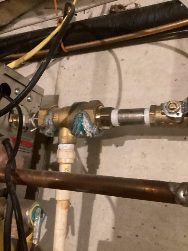 Conducted comprehensive plumbing inspection following home inspector's findings. Documented aging steam heating system serving master bathroom with corroded brass fittings showing significant oxidation and patina buildup. Identified lift pump tube requiring proper capping to prevent carbon dioxide infiltration. Located waste line with improper putty repair requiring correction. Photographed existing copper piping infrastructure, pressure relief valve assembly, and water heater connections to provide detailed assessment for recommended repairs including steam system servicing and new supply line installation.