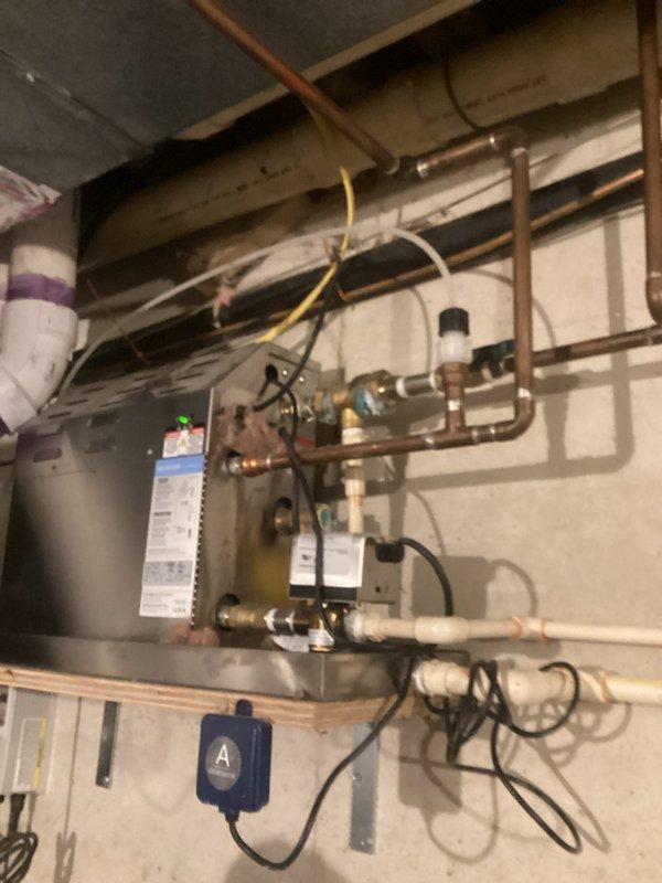 Conducted comprehensive plumbing inspection following home inspector's findings. Documented aging steam heating system serving master bathroom with corroded brass fittings showing significant oxidation and patina buildup. Identified lift pump tube requiring proper capping to prevent carbon dioxide infiltration. Located waste line with improper putty repair requiring correction. Photographed existing copper piping infrastructure, pressure relief valve assembly, and water heater connections to provide detailed assessment for recommended repairs including steam system servicing and new supply line installation.