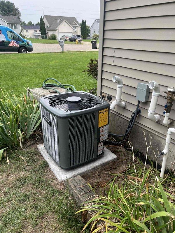 Completed full HVAC system replacement including outdoor condensing unit and indoor furnace. Removed existing equipment and installed new dark green condenser unit on concrete pad with proper clearances, connected refrigerant lines, and ran electrical conduit with disconnect box mounted to exterior wall. Installed new furnace in basement utility area with white PVC intake and exhaust venting routed vertically through exterior wall. Connected supply and return ductwork to new furnace, verified all electrical connections, and tested system operation. All equipment properly labeled, condensate drainage configured, and installation meets code requirements for residential HVAC systems.