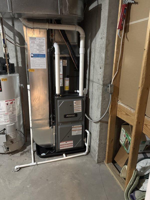 Completed full HVAC system replacement including outdoor condensing unit and indoor furnace. Removed existing equipment and installed new dark green condenser unit on concrete pad with proper clearances, connected refrigerant lines, and ran electrical conduit with disconnect box mounted to exterior wall. Installed new furnace in basement utility area with white PVC intake and exhaust venting routed vertically through exterior wall. Connected supply and return ductwork to new furnace, verified all electrical connections, and tested system operation. All equipment properly labeled, condensate drainage configured, and installation meets code requirements for residential HVAC systems.