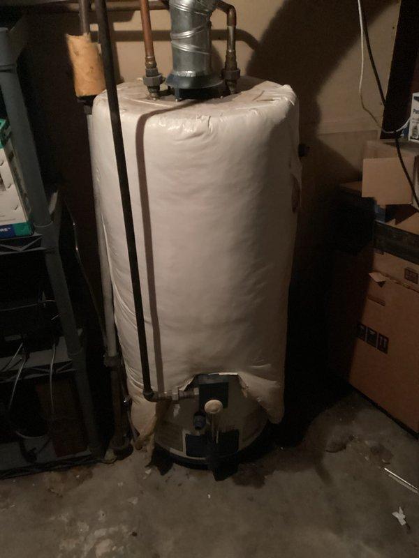 Completed water heater estimate for residential property. Assessed existing water heater unit in basement utility area, noting standard residential configuration with copper supply lines, metallic flue adapter, and flexible aluminum exhaust vent ducting. Observed insulation blanket installed on unit for energy efficiency, with visible floor staining around base indicating potential previous moisture concerns. Documented equipment condition and installation specifications through photographic records to provide comprehensive replacement estimate for homeowner consideration.