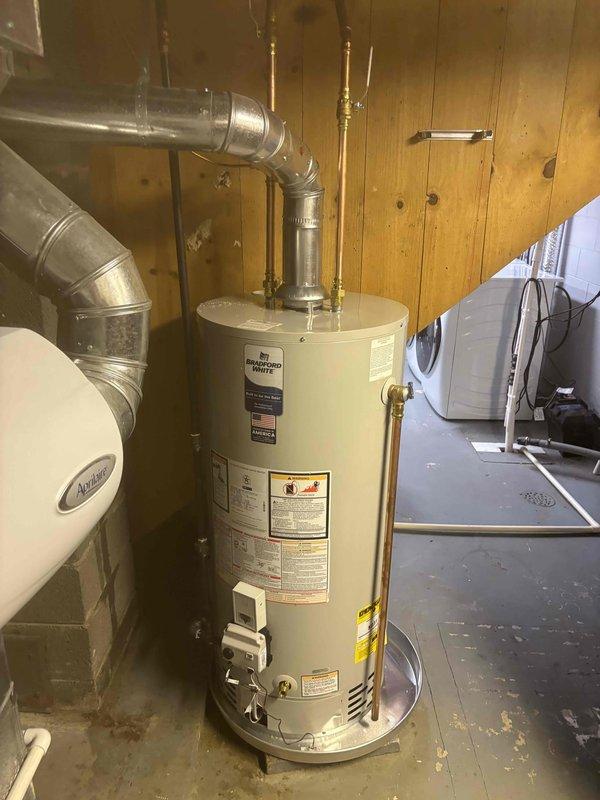 Replaced existing 50-gallon water heater with new Bradford White 40-gallon short natural gas water heater (Model BW246SN, Serial CFS7473807) installed in basement utility room beneath existing water tank. Unit features 40,000 BTU/hr input rating with 6-inch vent connector and meets ANSI Z21.10.1-2015 standards for closet installation clearances. Connected copper supply and discharge piping with brass fittings to integrate with existing plumbing system. Verified proper gas pressure settings, tested all connections for leaks, and confirmed unit operation according to manufacturer specifications.