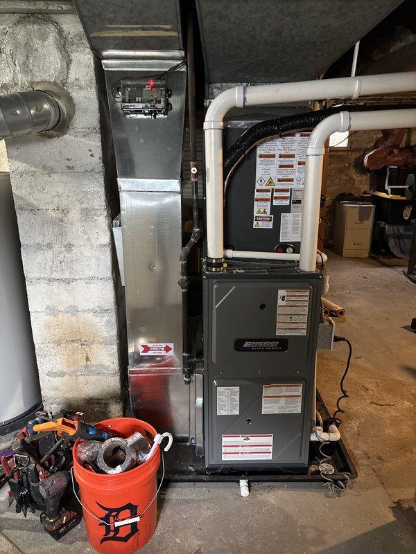 Successfully completed add-on air conditioning system installation to existing forced-air heating system. Installed new outdoor condensing unit on concrete pad with proper clearances from structure and window well. Unit positioned on side of residence with appropriate electrical disconnect and refrigerant line connections. Connected AC system to existing furnace infrastructure in basement mechanical room, integrating with current ductwork distribution system. Ran refrigerant lines from outdoor condenser to indoor evaporator coil, properly insulated and secured. Installed condensate drain piping using PVC, routed to appropriate drainage location. Charged system with refrigerant to manufacturer specifications using manifold gauges. Verified proper airflow, superheat, and subcooling values. Tested system operation through complete cooling cycle, confirming proper compressor function, fan operation, and temperature differential across evaporator coil. All installation work completed per ma