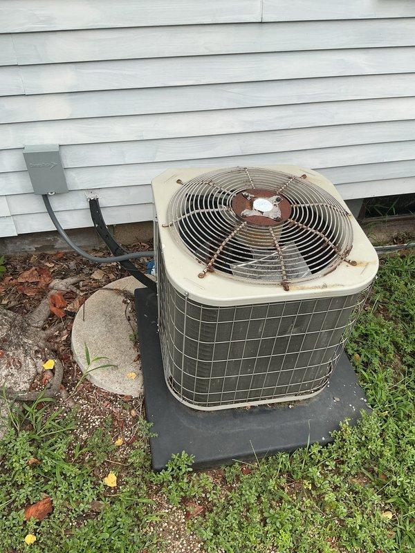 Completed annual cooling maintenance on a 13-year-old Payne air conditioning system. Performed comprehensive tune-up including inspection of outdoor condenser unit and indoor furnace components. Outdoor unit showed age-appropriate wear with surface rust and weathering on cabinet panels; confirmed proper mounting on concrete pad and verified electrical connections at disconnect box. Inspected indoor HVAC system, noting PVC exhaust pipe with previous duct tape repairs on joints. Documented system condition through photographs for maintenance records.